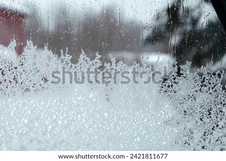 View through a window on a windy, rainy, and snowy day outdoors.