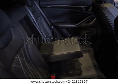 Armrest with cup holder inside. Leather comfortable white passenger seats and armrest. White leather interior of the luxury modern car. Modern car interior details. Rear passenger seats. Royalty-Free Stock Photo #2421815857
