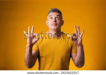 Portrait of man meditating, keeping calm, over yellow background. Relaxation concept