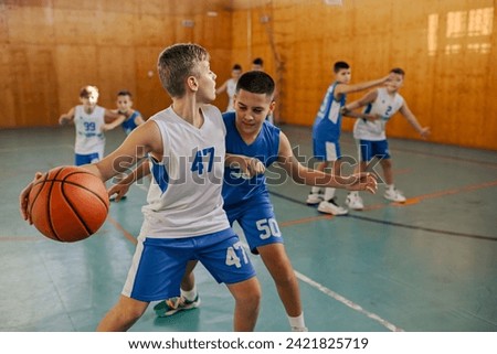 A young basketball players in action are practicing basketball at indoor court during the training. Dynamic picture of a basketball kids practicing moves and game tactics during the game on training.