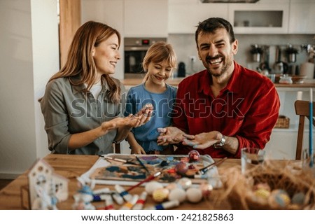 Joyful father, mother and daughter engaged in Easter egg decorating, sharing smiles and laughter	 Royalty-Free Stock Photo #2421825863