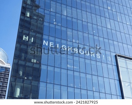 A sign "Hi Neighbours! :)" layed out in a glass office building in Warsaw, Poland