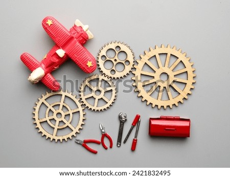 Flatlay picture of wooden gear with aeroplane, repairing tools and toolbox. Technical and mechanical support concept