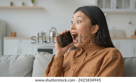 Excited Asian woman businesswoman talk phone in kitchen listen good news feel shock surprised korean chinese girl speaking cellphone enjoy mobile call discuss news laugh talking laughing win success Royalty-Free Stock Photo #2421834945