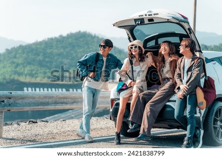 Group of Asian generation z people friends sitting on car trunk looking beautiful nature of countryside. Man and woman friendship enjoy and fun outdoor lifestyle road trip on summer holiday vacation. Royalty-Free Stock Photo #2421838799