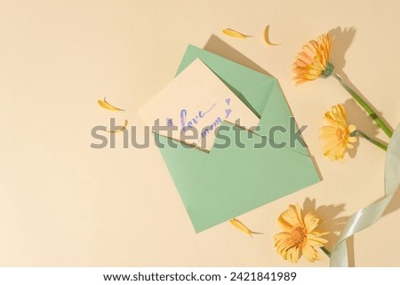 View from above of an opened envelope featured a paper inside with the text “love mom” and yellow flowers. International Women's Day also marks a call to action for accelerating gender parity