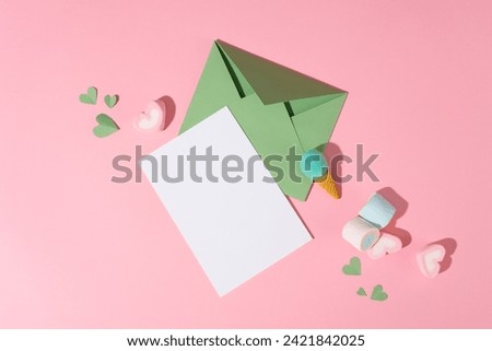 Marshmallows, candy and paper hearts decorated over pink background with a white paper and green envelope. Elegant card for International Women's Day. Banner or leaflet for March 8. Copy space