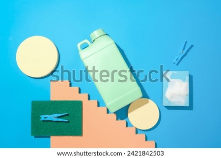Round platforms, a bottle of detergent, a sponge and clothespins are placed on a blue background. Mockup of cleaning products for advertising. Flat lay.