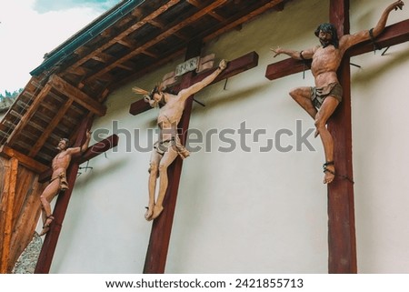 Jesus Christ and two martyrs crucifixion on wooden crosses in the Church of St. Leonard.Church of St. Leonard in Lungau, Austria. August 2023. Catholic Church architecture outside. 