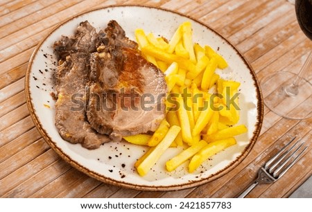 Pork chop with fried French fries on a plate.