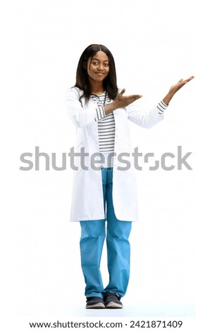 A female doctor, on a white background, in full height, points to the side