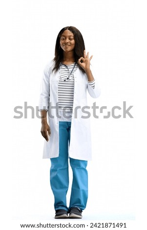 A female doctor, on a white background, in full height, shows the ok sign