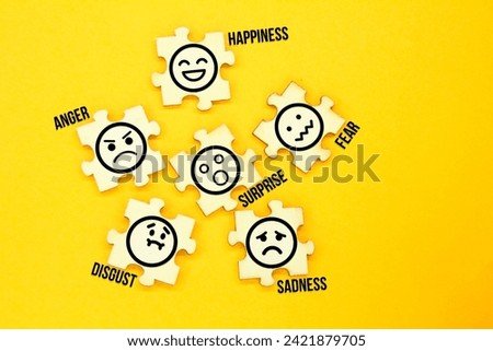 wooden puzzle with icons of 6 facial expressions and the words anger, happiness, fear, surprise, disgust and sadness Royalty-Free Stock Photo #2421879705