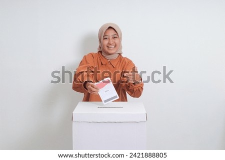 Portrait of Asian hijab woman inserting and putting the voting paper into the ballot box. General elections or Pemilu for the president and government of Indonesia. Isolated image on white background