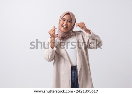 Portrait of excited Asian hijab woman in casual suit making korean heart sign means love to you. Showing sympathy and caring feelings. Isolated image on white background