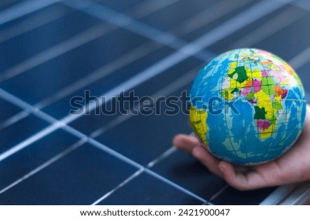 Girl's hands with a globe with a background of solar panels Concept of saving the world with renewable energy.