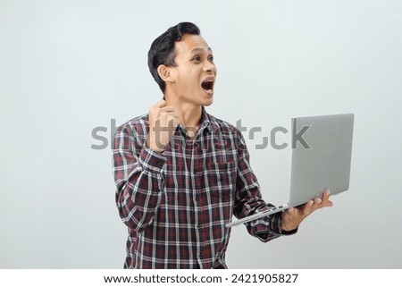Happy asian indonesian man holding laptop computer on isolated background