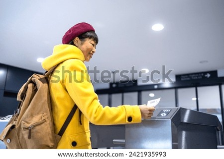 Female passenger with backpack validating boarding pass ticket at the train station. Royalty-Free Stock Photo #2421935993
