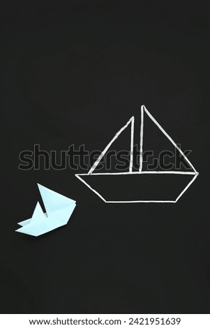 Drawn and colorful paper boats on black chalkboard