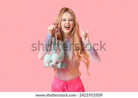 Beautiful young happy woman with vintage roller skates showing "devil horns" gesture on pink background