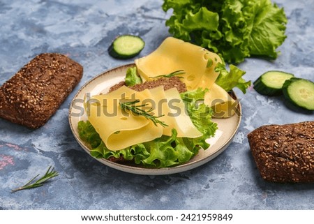 Tasty sandwiches with cheese and lettuce in plate on blue background, closeup Royalty-Free Stock Photo #2421959849