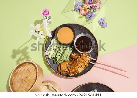 Peking duck with condiments and surreal floral decor, ideal for modern Asian culinary presentation.