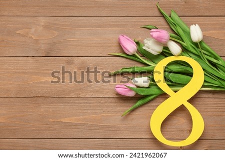 Figure 8 made of paper and beautiful tulips on wooden background. International Women's Day