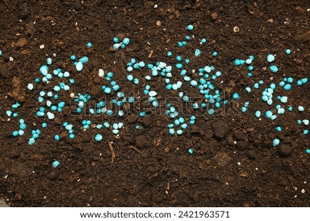 Brown soil with blue granular fertilizer Royalty-Free Stock Photo #2421963571