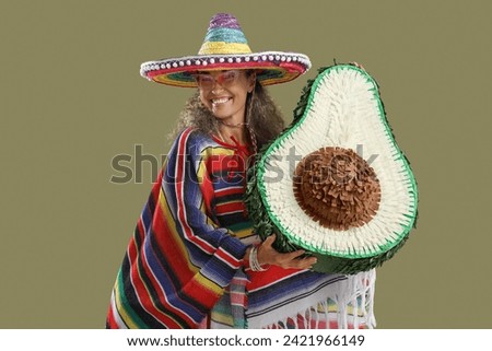 Mature woman in sombrero hat with pinata on color background. Mexico's Day of the Dead (El Dia de Muertos) celebration Royalty-Free Stock Photo #2421966149