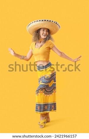Mature woman in sombrero hat dancing on yellow background. Mexico's Day of the Dead (El Dia de Muertos) celebration Royalty-Free Stock Photo #2421966157