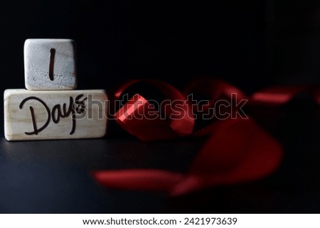 Baby's age milestone written on a wooden cube with a red ribbon on a black background