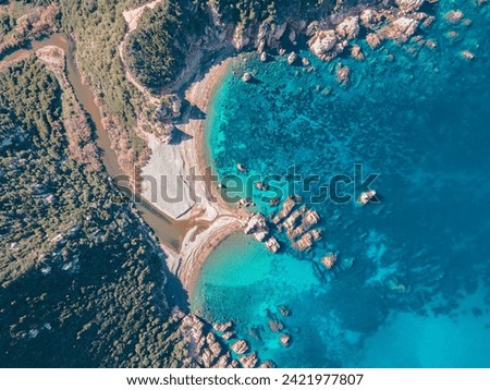 Zenithal photo of the splendid Cala Tinnari beach on the Paradiso coast in Northern Sardinia. The wild nature with the river flowing into the beautiful blue sea makes the image exciting.
