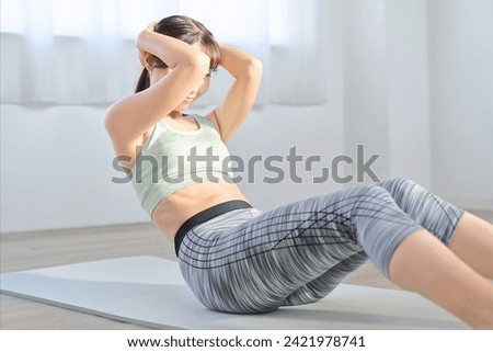 Woman training her abdominal muscles with crunches Royalty-Free Stock Photo #2421978741