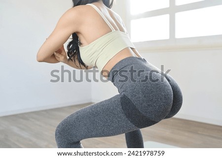 A woman training her lower body with squats Royalty-Free Stock Photo #2421978759