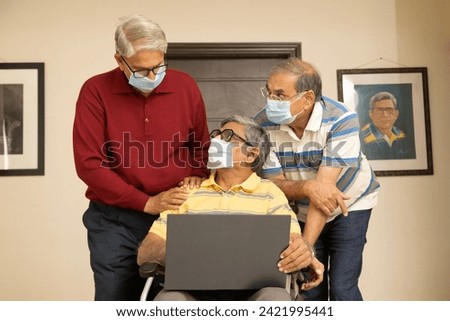 Three senior friends working on laptop while wear face mask due to coronavirus covid-19 pandemic