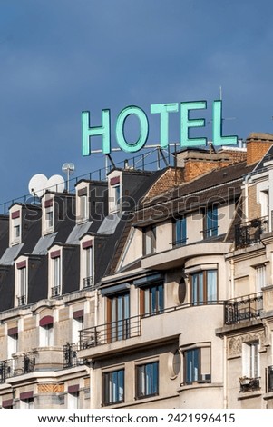 Sign with the word 'HOTEL' written in bright capital letters on the top of a building in Paris, France