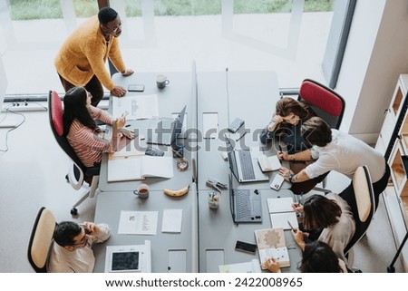 Multicultural coworkers collaborating in a modern office, achieving successful results through teamwork and technology. Royalty-Free Stock Photo #2422008965