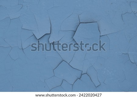 Blue peeling paint on the wall. Old concrete wall with cracked flaking paint. Weathered rough painted surface with patterns of cracks and peeling. High resolution texture for background and design. Royalty-Free Stock Photo #2422020427