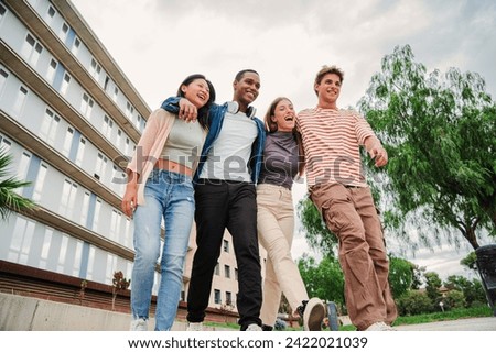 Group of young multiracial high school students walking and talking together. University classmates using a cellphone. Happy university friends carrying backpacks and having a conversation Slow motion Royalty-Free Stock Photo #2422021039