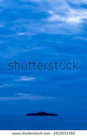 The small lighthouse island between the blue sky and the blue sea