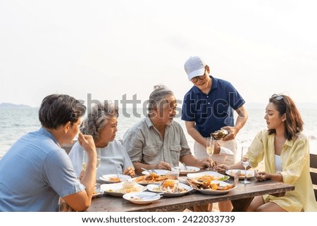 Happy Asian family enjoy and fun outdoor lifestyle travel nature and having dinner sea food at tropical beach on summer vacation. Adult couple and aging parents celebration holiday party together.