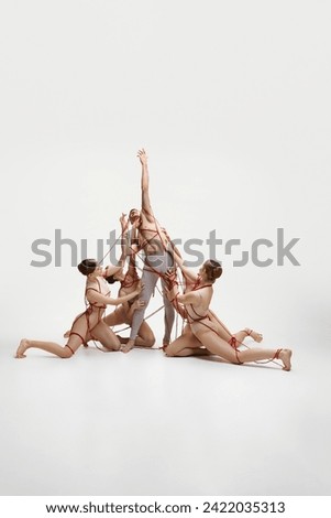 Reach out of comfort zone. Ballet dicers connected with red strings performing against white studio background. Social manipulation. Concept of classical dance, modern style, inspiration