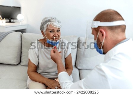 Professional medical young male worker wearing personal protective equipment testing senior woman for dangerous disease using test stick. Nasal mucus testing for viral infections. 