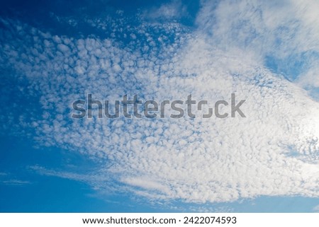 Blue sky with white altocumulus clouds. Background on the theme of weather and ecology.