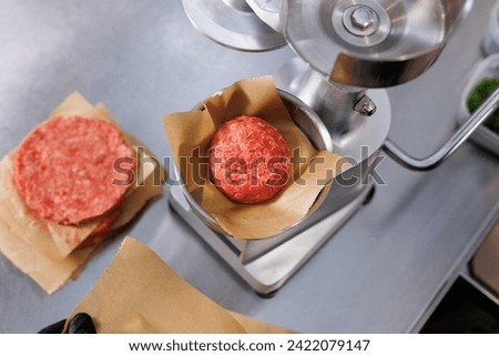 A cook using a press to make hamburger patties Royalty-Free Stock Photo #2422079147