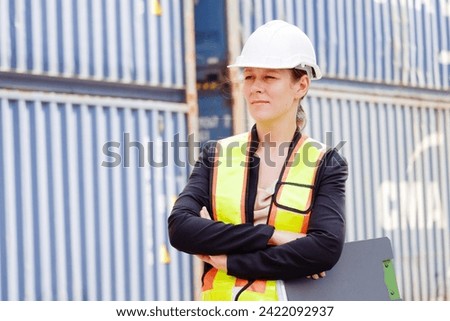 Female engineer wearing safety helmet working at container warehouse.