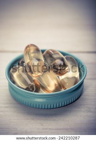 Cod liver oil omega 3 gel capsules isolated on wooden background. Vitamin D pills.  dietary supplement