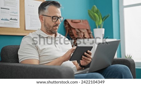 Grey-haired man business worker using touchpad and laptop at the office