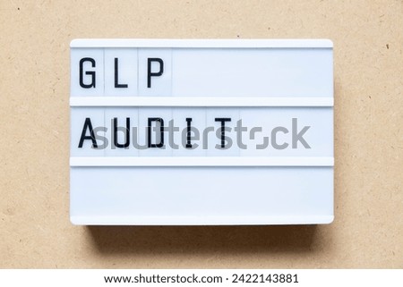 Lightbox with word GLP (Abbreviation of Good laboratory practice) audit on wood background