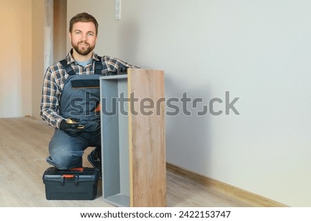 Professional Furniture Assembly Worker Assembles Shelf. Professional Handyman Doing Assembly Job Well, Helping People who Move into New House. Royalty-Free Stock Photo #2422153747